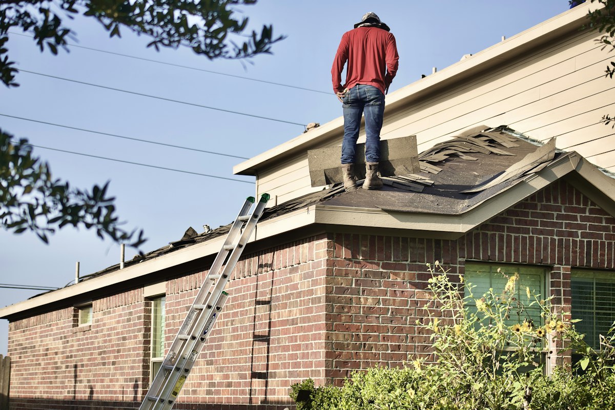 A roofer standing on a half-stripped roof
